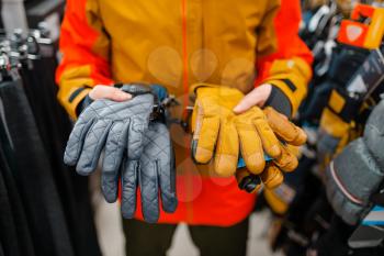 Man trying on gloves for ski or snowboarding, sports shop. Winter season extreme lifestyle, active leisure store, male customer with protect equipment