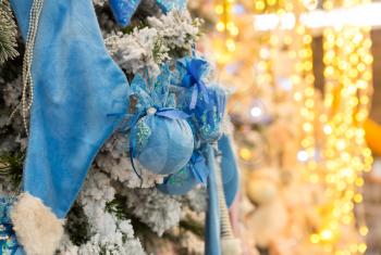 Christmas tree decorated with blue balls and lights, garland closeup. Xmas decor, new year. Winter holiday celebration