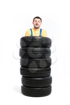 Tyre service, worker is standing inside a pile of tires, white background, repairman, wheel mounting