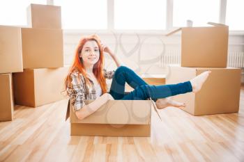 Woman sitting in carton box, housewarming. Moving to new housing