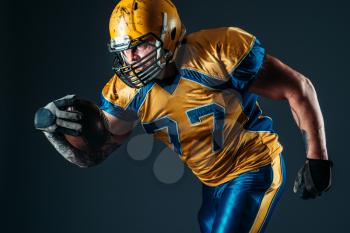 American football offensive player with ball in hand, national league, black background. Contact sport