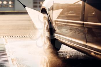 Male worker wash the car with high pressure washer. Car-wash station