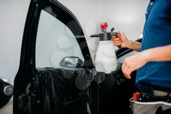 Male hand with spray, car window tint installation process, installing procedure, tinting film