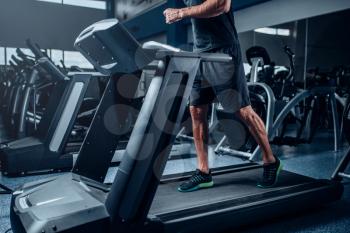 Male person workout on running exercise machine. Active sport training in gym