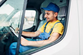 Cargo delivery service, male driver courier in uniform sitting in cab of truck. Distribution business