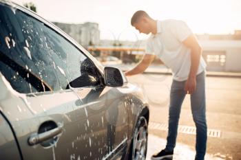 Washer rubbing vehicle with foam, automobile in suds, car wash. Carwashing station