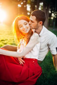 Love couple kissing in summer park on sunset. Romantic date of attractive woman and young man