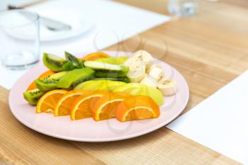 Fresh orange, kiwi and banana pieces on a plate. Tropical fruits on dessert, ripe healthy food