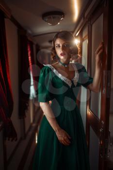 Railway journey, woman in retro dress, vintage train compartment interior. Old wagon. Railroad voyage