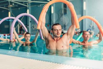 Aqua aerobics exercises, women with male trainer, indoor swimming pool.