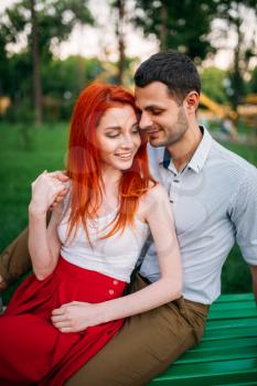 Beautiful love couple leisure on a bench, romantic meeting outdoors. Young woman and man happy together