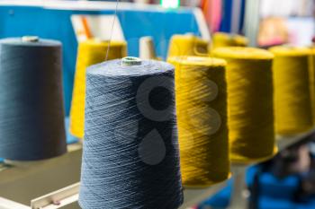 Spools of color threads closeup, sewing equipment. Cloth factory, weaving, textile production, clothing industry