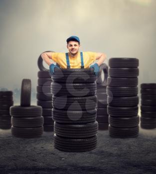 Service worker is standing inside a pile of tires, tyre industry, repairman, wheel mounting