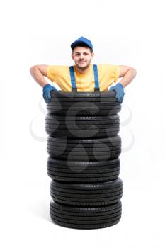 Tyre service, worker is standing inside a pile of tires, white background, repairman, wheel mounting
