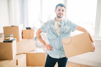 Smiling young man holds carton box in hands, housewarming. Moving to new house