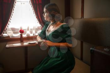 Woman in vintage train, rich retro compartment interior. Old wagon. Railway journey, railroad voyage