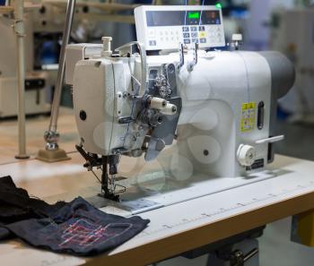 Sewing machine and cloth in cutting shop, nobody, clothing factory. Fabric production, sew manufacturing, needlework technology