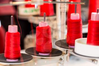 Spools of red threads on sewing machine. Cloth fabric, weaving, textile production, clothing industry