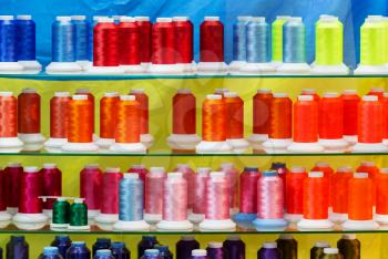 Spools of new color threads, sewing equipment. Cloth factory, weaving, textile production, clothing industry