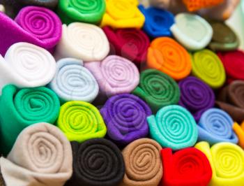 Colorful towels rolled into a tube closeup. Shelf with textile, shop showcase