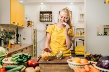 Female person cooking on the kitchen, healthy organic food preparing. Vegetarian diet, fresh vegetables and fruits on wooden table