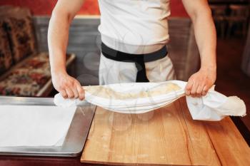 Male chef prepares classical apple strudel, top view, bakery cooking. Homemade sweet dessert, preparation process