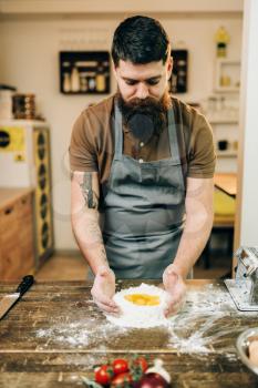 Homemade pasta cooking, bearded chef preparing dough on wooden kitchen table