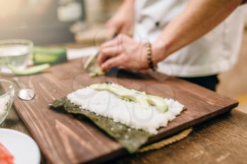 Male cook hands, making sushi rolls, seafood. Traditional japanese cuisine, preparation process
