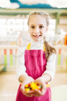 Happy little girl holds in hands handmade caramel sweets. Fresh lollipop in candy store
