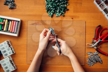 Female person hands with scissors, top view. Handmade jewelry. Needlework, bijouterie making