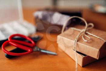 Needlework gift and scissors on wooden table. Handicraft tools. Handmade accessories