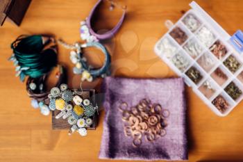 Box with equipment for needlework, bracelets on wooden table, top view. Handmade jewelry. Handicraft, bijouterie making