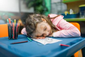 Little girl sleep in play area after drawing, pet shop. Tired kid in petshop, goods for customers and domestic animals