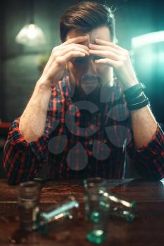 Sad man sitting at the bar counter, alcohol addiction. Male person in pub, alcoholism