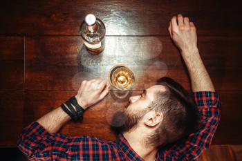 Drunk man sleeps at the bar counter, top view, alcohol addiction. Male person in pub, alcoholism