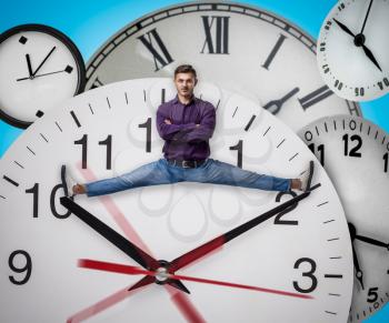 Man sitting on the twine between arrows of a huge clock. Deadline concept, time does not stop