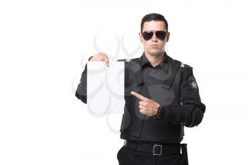 Seriuse cop in sunglasses points to an empty piece of paper, black uniform with body armor, white background. Policeman in special ammunition