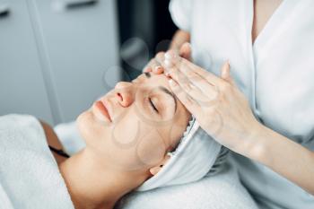 Face massage to female patient, cosmetology clinic. Facial skincare, rejuvenation procedure in spa salon