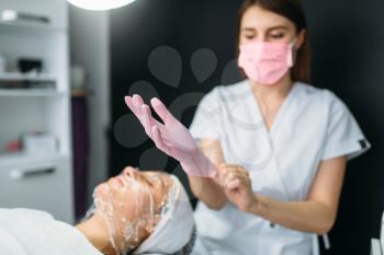 Beautician wears gloves against patient with face mask, getting rid of wrinkles, cosmetology clinic. Facial skincare, rejuvenation procedure in spa salon, health care