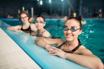 Female swimmers in goggles on workout in swimming pool. Women in swimwear on training, water sport 