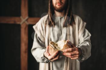 Jesus Christ gives bread to the faithful, sacred food, crucifixion cross on background. Son of God, christianity