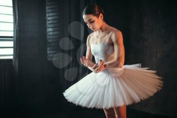 Beautiful ballerina in white dress dancing in studio. Classical ballet dancer training in class
