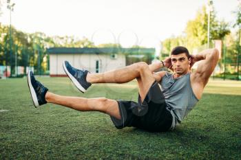Male athlete doing exercises on the press on outdoor fitness workout. Strong sportsman on sport training in park
