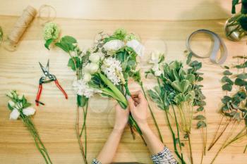 Female florist cuts roses with pruner, fresh bouquet preparation process. Floral business, flowers decoration