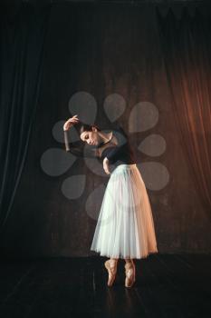 Classical ballet dancer in motion on the stage in theatre. Graceful ballerina poses in studio