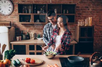Love couple cooking on the kitchen, vegetable salad preparation. Fresh diet food. Man and woman prepares romantic dinner