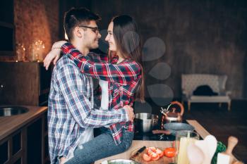 Young love couple hugs on the kitchen while cooking vegetable breakfast. Man and woman embrace, happy family before cooking romantic dinner