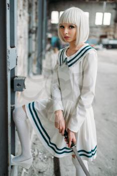 Pretty anime style blonde girl with sword. Cosplay fashion, asian culture, doll with blade on abandoned factory, cute woman with makeup