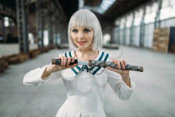 Pretty anime style blonde lady with sword. Cosplay fashion, asian culture, doll with blade, cute woman with makeup in the factory shop