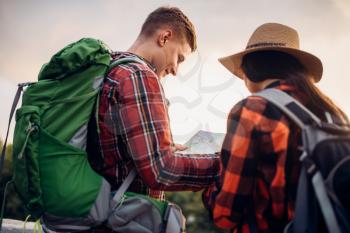 Hikers with backpacks looks on map, excursion in tourist town. Summer hiking. Hike adventure of young man and woman